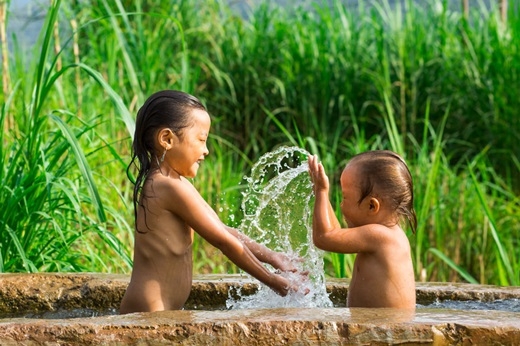 Hai chị em cùng chơi đùa rất vô tư trong hồ nước trên đường. (Ảnh: Rehahn)